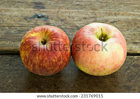Two apple on weathered wooden garden or park table.