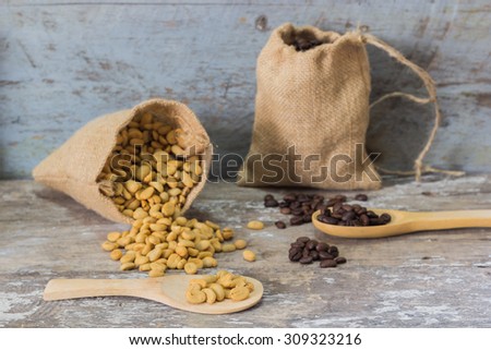 coffee beans in sack bag and spoon on roasted coffee seed background.