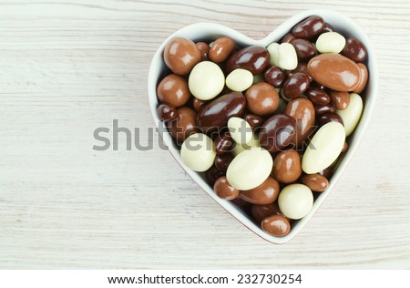 chocolate covered nuts and raisins in a heart-shaped bowl