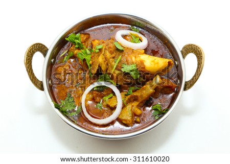 Indian style meat dish or mutton curry in a copper brass bowl isolated on white background.
