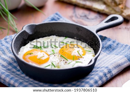 fried eggs with chives in an iron pan on a wooden table 商業照片 © 