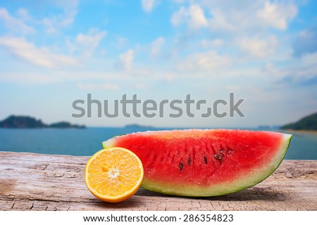 Watermelon slice and Orange slice on wooden and beach background with clipping part