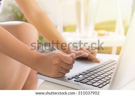 Woman hold Credit Card on laptop waiting for online shopping in morning light,soft focus.
