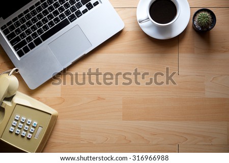 Office table with computer notebook,phone and coffee cup. View from above with copy space,vintage effect.