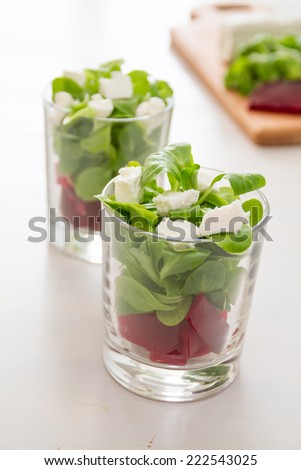 Beet root salad served in glasses on white wood background