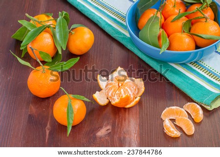 Mandarins in blue bowl and on brown wood table, mandarin slices