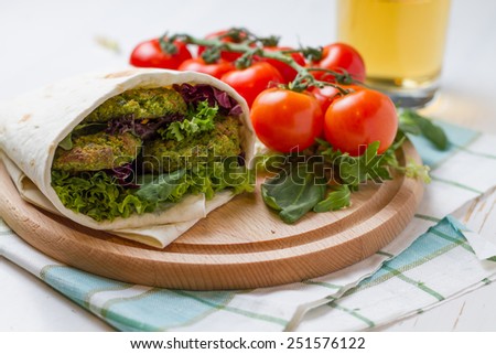 Falafel served wrap with tahina sauce, beer and tomatoes, white wood background