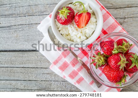 Cottage cheese with strawberries on plaid napkin, rustic wood background, top view