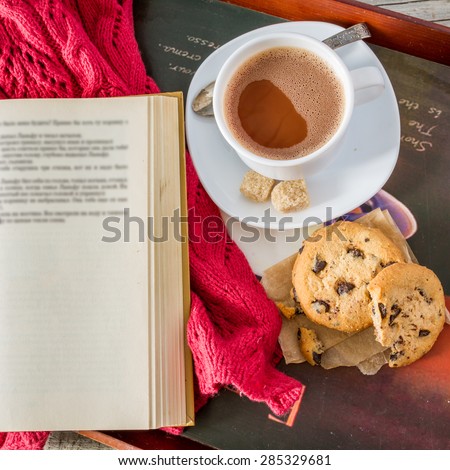Autumn lifestyle - hot chocolate, chocolate chip cookies, old book, tray, warm blanket, rustic wood background, top view