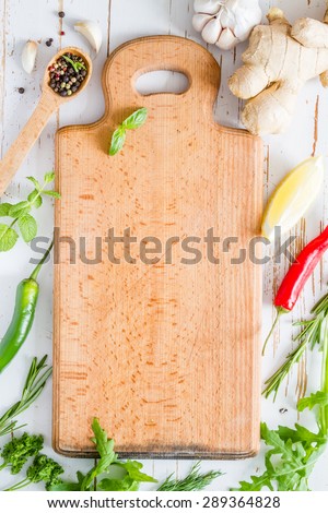 Herbs background - board, chili, lemon, mint, parsley, basil, garlic, ginger, rosemary,  white wood background, top view
