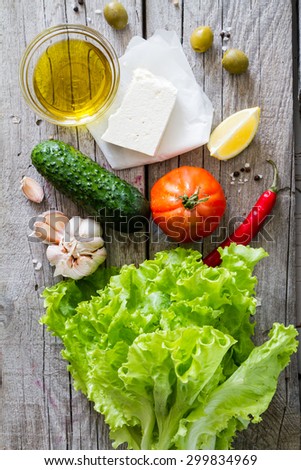 Greek salad ingredients, rustic wood background, top view