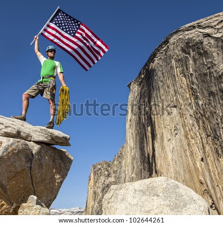 Climber waves an american flag on the summit after a challenging ascent.