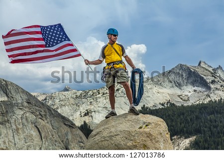 Rock climber raises the flag on the summit after a successful and challenging ascent.