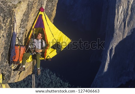 Climber in his hanging camp sleeps on the side of a mountain.