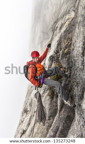 Rock climber rappels  on a challenging cliff.