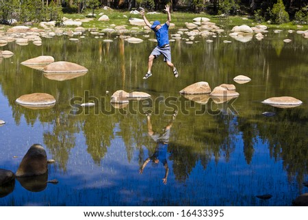 A hiker jumps his way across a high alpine lake in Tuolumne Meadows, Yosemite National Park.