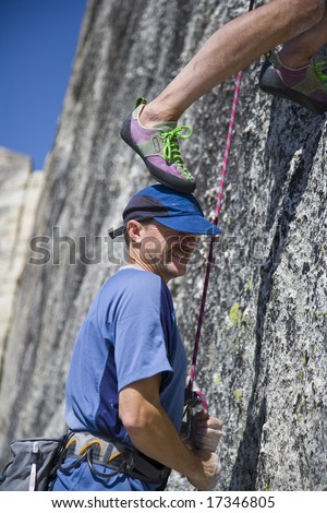 A rock climber using his partners head as a foothold in Yosemite National Park on a summer afternoon climbing adventure.