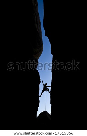 Rock climber silhouetted as he climbs up a chimney in Joshua Tree National Park, California, on a summer day.