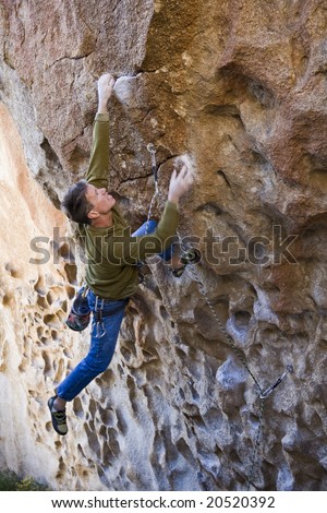 Climber clinging to rock face in Joshua Tree National Park, California.