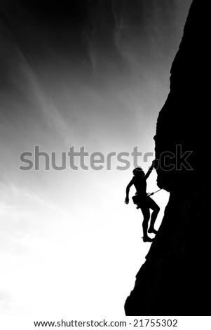 A climber is silhouetted against the evening sky as she clings to a steep rock face in Joshua Tree National Park, California.