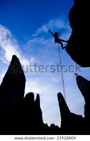 A climber rappelling from the summit of a rock spire is silhouetted against the evening sky in The Sierra Nevada Mountains.