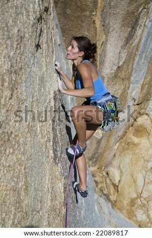 Female climber ascending a steep rock face in Joshua Tree National Park.