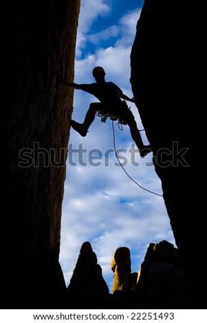 Climber clings to the edge of a steep rock precipice in The Sierra Nevada Mountains, California.