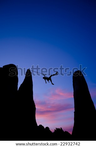 A climber is silhouetted as she pulls herself across a gap between two pinnacles, in the Sierra Nevada  Mountains, California.