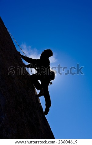 A climber is silhouetted as he makes his way up a steep rock face in the Sierra Nevada Mountains, California.