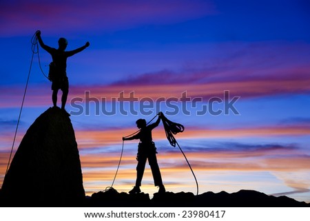 Team of climbers silhouetted as they coil ropes after reaching the summit of a rock pinnacle in The Sierra Nevada Mountains, California.