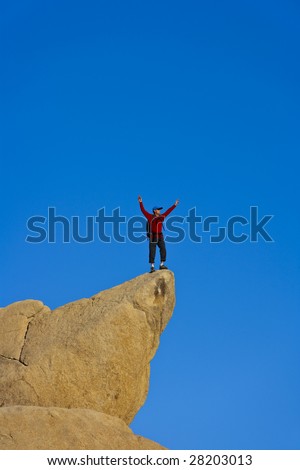 Climber on the summit of a rock spire after a successful ascent, in the Sierra Nevada Mountains, California.