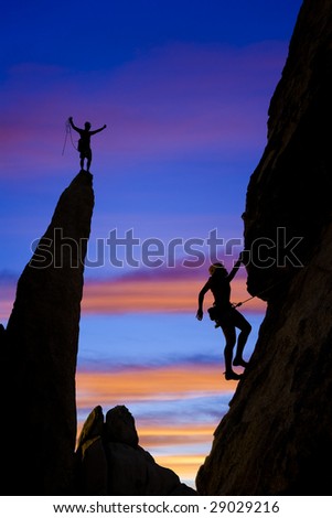 A team of climber is silhouetted against the evening sky as they ascend a steep rock face in Joshua Tree National Park, California.