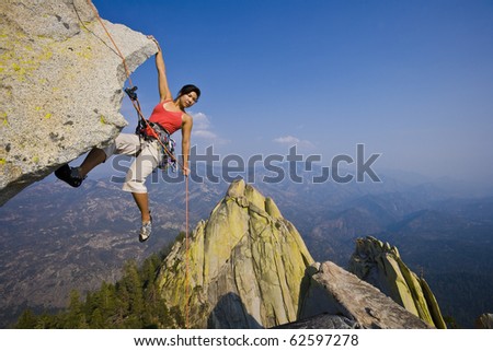 Female climber rappelling from the summit of an overhanging cliff.