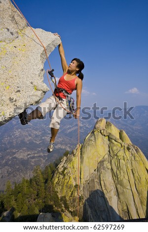 Female climber rappelling from the summit of an overhanging cliff.