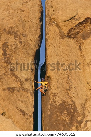 Rock climber struggles for his next grip on a challenging ascent.