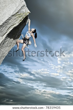 Rock climber struggles for her next grip on a challenging ascent.