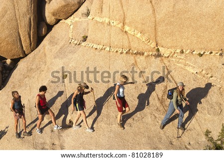 Female hiking team climbs to the summit of a challenging rock spire in Joshua Tree National Park.