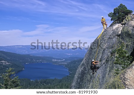 Team of rock climbers struggle up a challenging cliff.