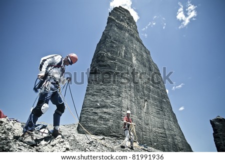 Team of rock climbers struggle up a challenging cliff.
