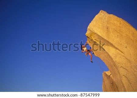 Female rock climber struggles for her next grip on a challenging ascent.