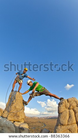 Team of climbers struggle to the summit of a rock pinnacle after a challenging ascent.