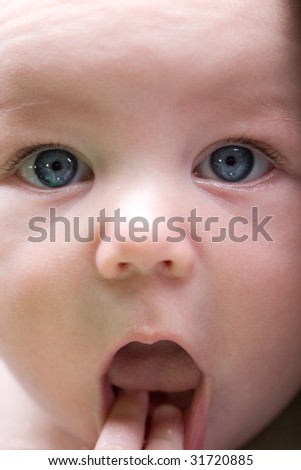 An adorable infant with very big blue eyes and a surprised expression.