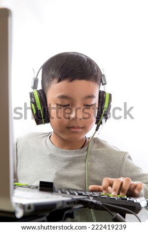 Asian kid play computer internet games and wear headset to communicate