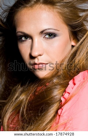 The portrait of a serious sexy girl in pink blouse with wind blowing in her face