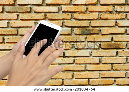 blur hand touching mobile phone on old dirty brick wall background