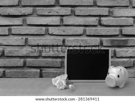 pink piggy bank and blackboard on old dirty brick wall background in black and white tone