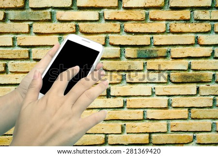 blur hand touching mobile phone on old dirty brick wall background