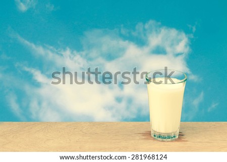 glass of cool milk on blur cloud on blue sky background in vintage tone