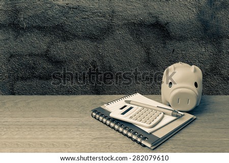 piggy bank calculator and writing tools on dark crack wall background