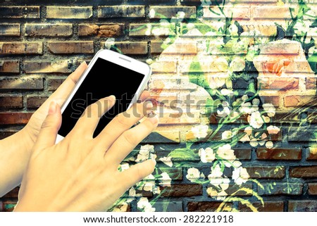 blur hand touching mobile phone on roses and old dirty brick wall background